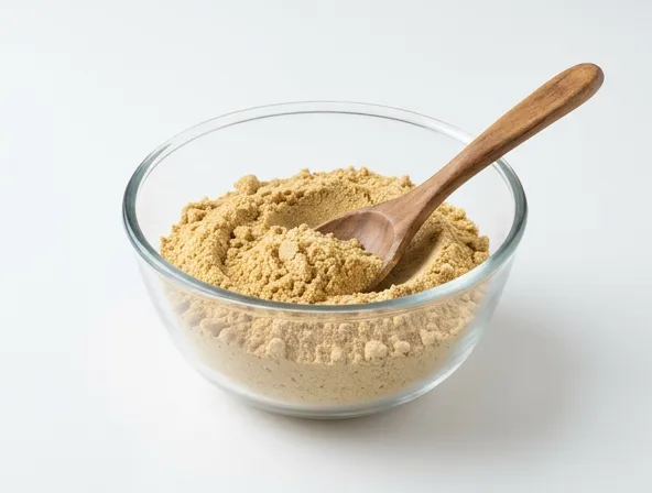 Sunflower protein powder in a clear mixing bowl with wooden spoon, clean white background